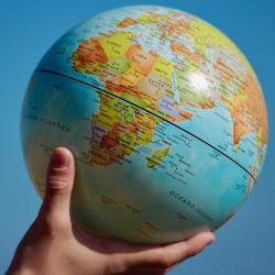 A hand holding up a globe